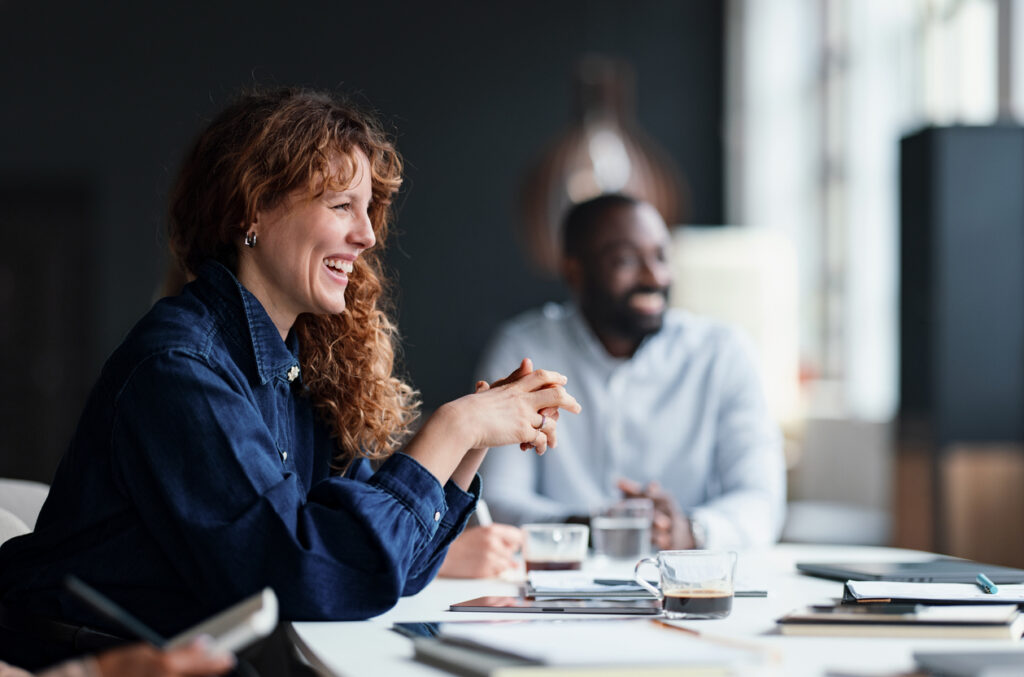 A group of professionals in a meeting, smiling and engaged in discussion, representing collaborative teamwork essential for successfully scaling enterprise AI agents.